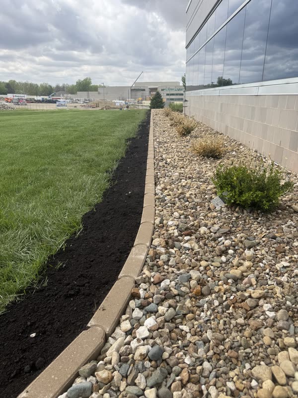 Long run of river rock and dark mulch against a building
