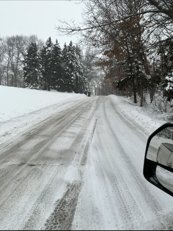 A private road cleared down to pavement while the snow is still falling